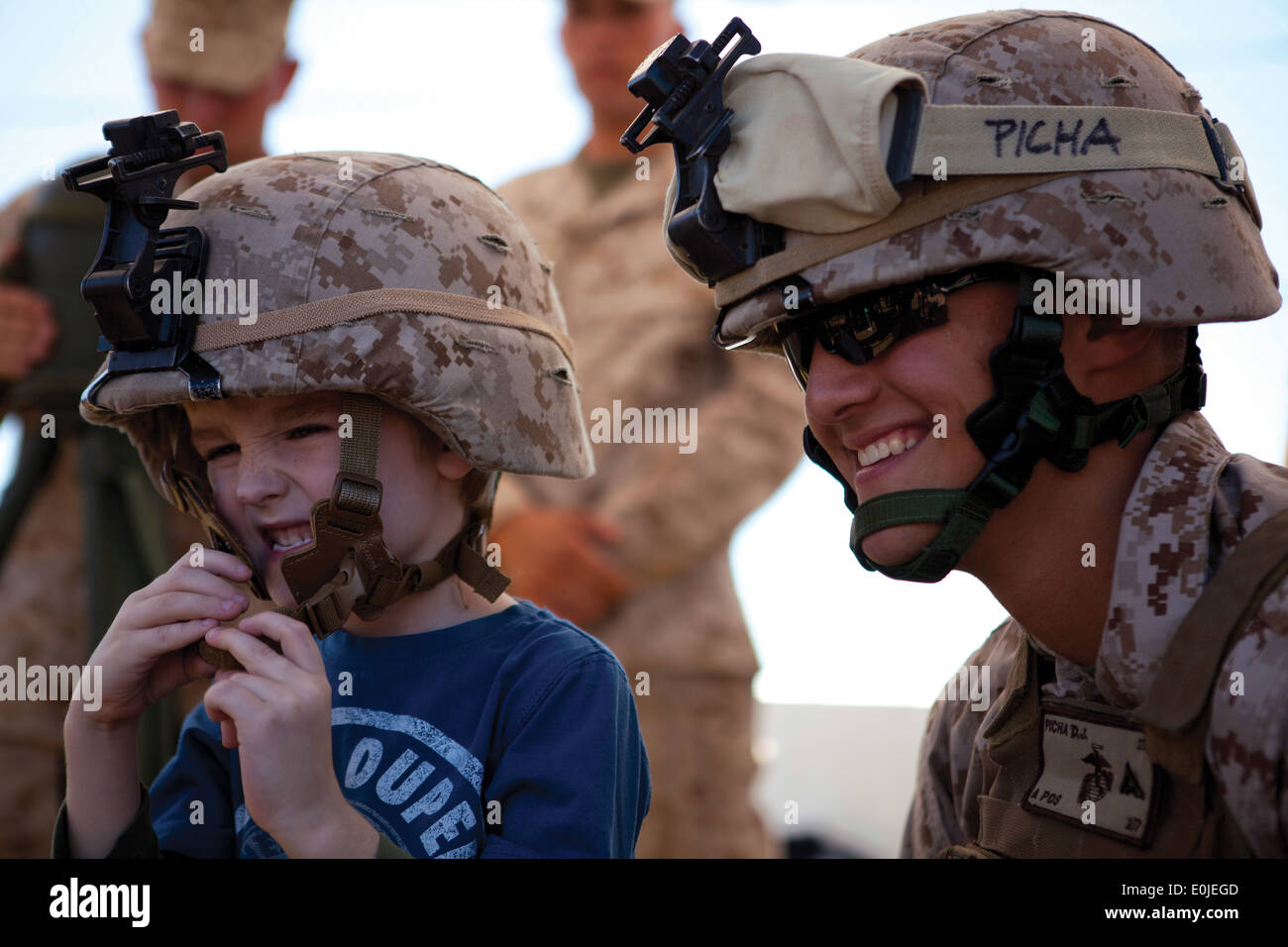 Lance Cpl. Don Picha, right, with 2nd Battalion, 7th Marine Regiment, poses for a picture with a child after letting him try on Stock Photo