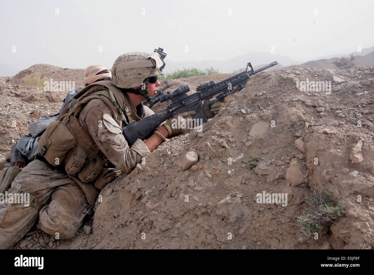 Seaman Apprentice Brian Rumbles, assigned to Golf Company, 2nd Battalion, 7th Marine Regiment, fires on two Taliban insurgents Stock Photo
