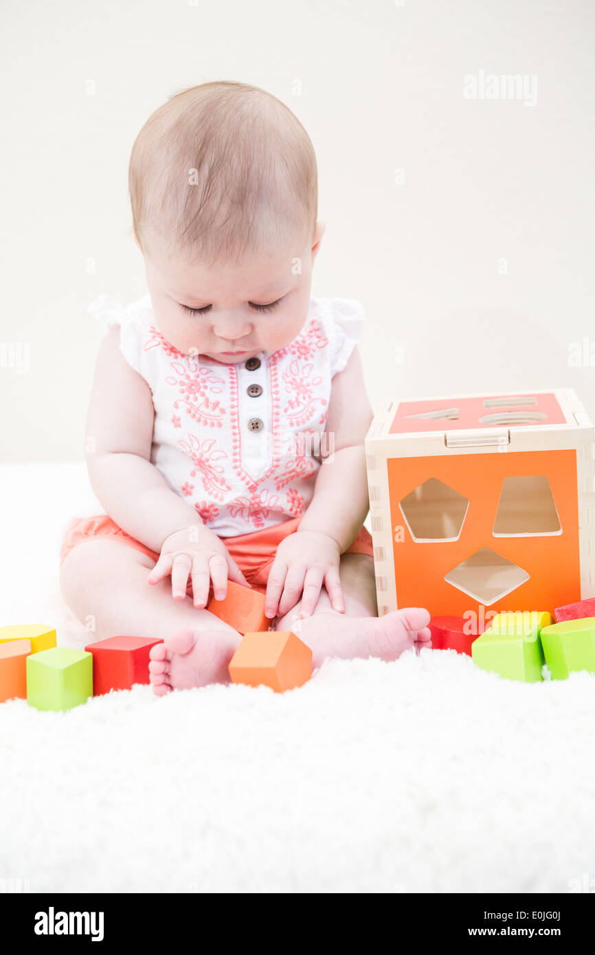 Baby girl playing with her toys on a white blanket Stock Photo - Alamy