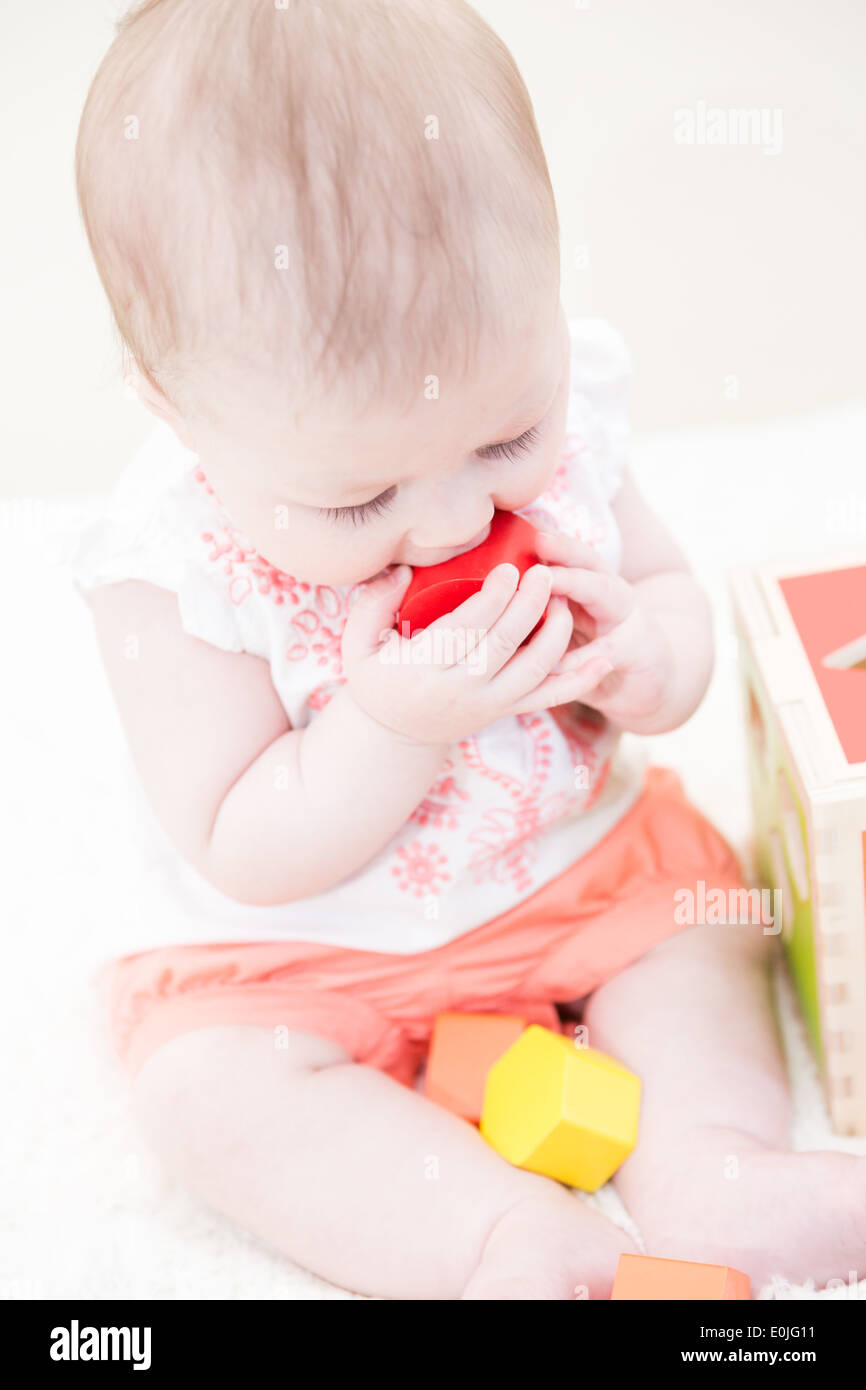 Baby girl playing with her toys on a white blanket Stock Photo - Alamy