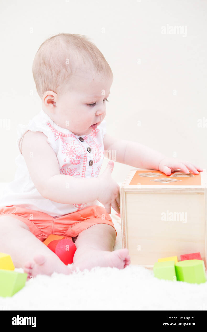 Baby girl playing with her toys on a white blanket Stock Photo - Alamy