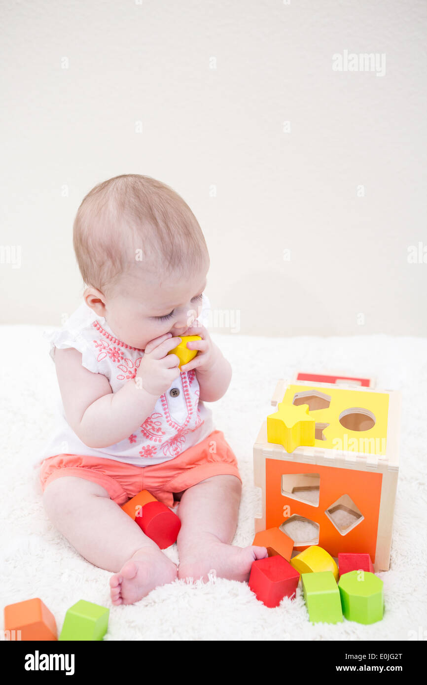Baby girl playing with her toys on a white blanket Stock Photo - Alamy
