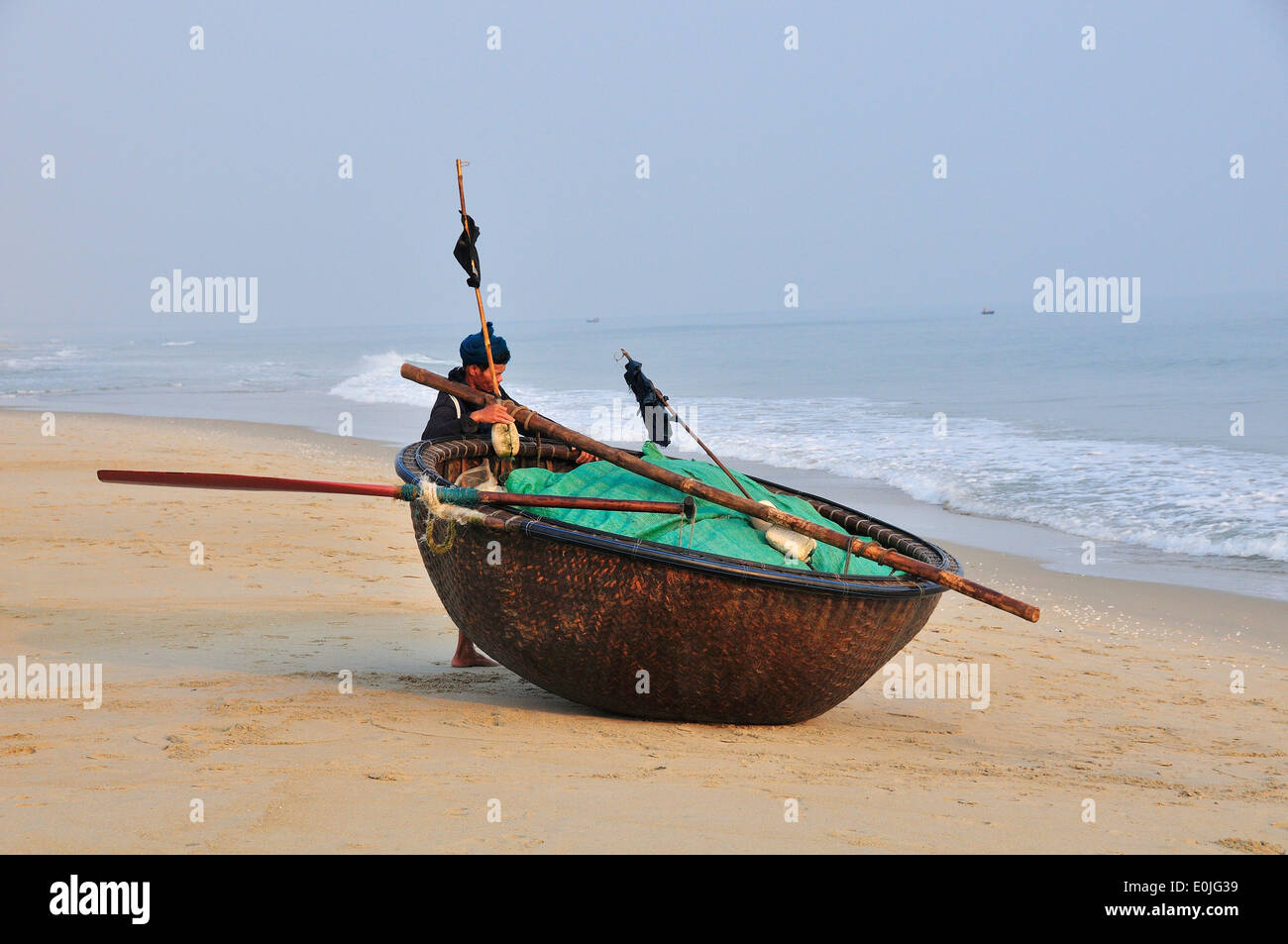 Fisherman pulling his coracle also called 'basket boat' or 'thung chai', woven from bamboo, up