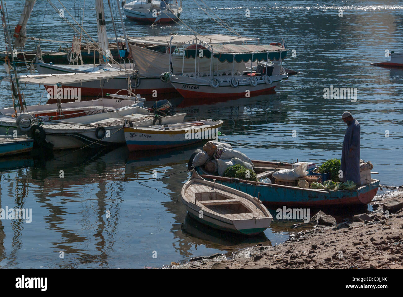 Man, his shopping and Boats, southern corner of Elephantine Island, near Nilometer, Aswan, Upper Egypt Stock Photo