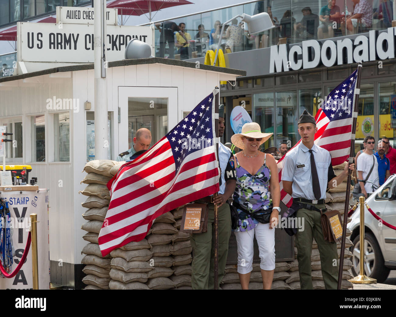Tourists posing at Checkpoint Charlie, in Berlin Germany, was a cold war crossing point between East and West Berlin. Stock Photo