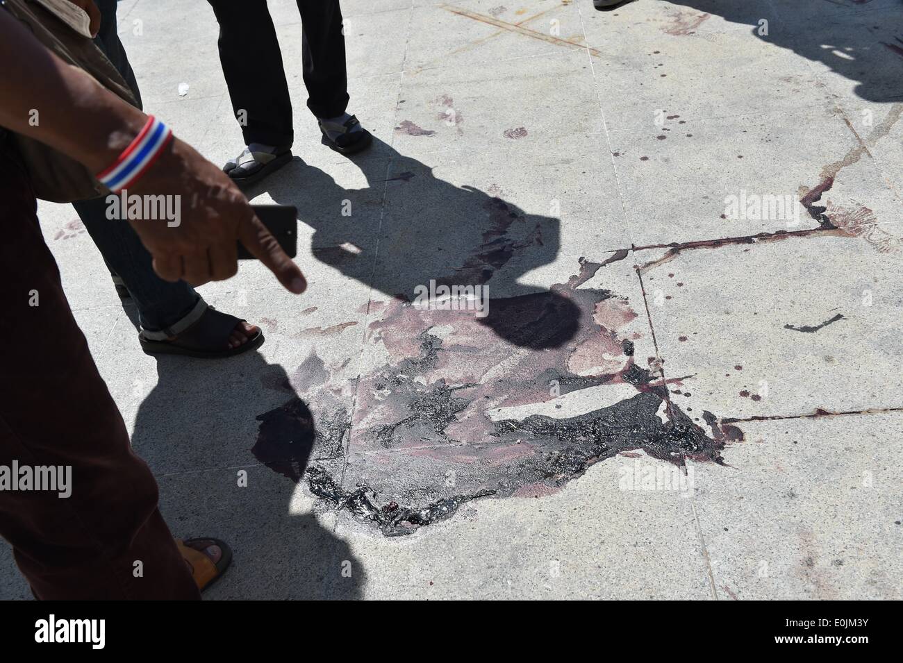 Bangkok, Thailand. 15th May, 2014. People look at the blood stains at the site of an attack near the Democracy Monument in Bangkok, Thailand, May 15, 2014. Two anti-government protestors were killed and 22 others injured in a gun and grenade attack here early Thursday, local media reported. © Lui Siu Wai/Xinhua/Alamy Live News Stock Photo