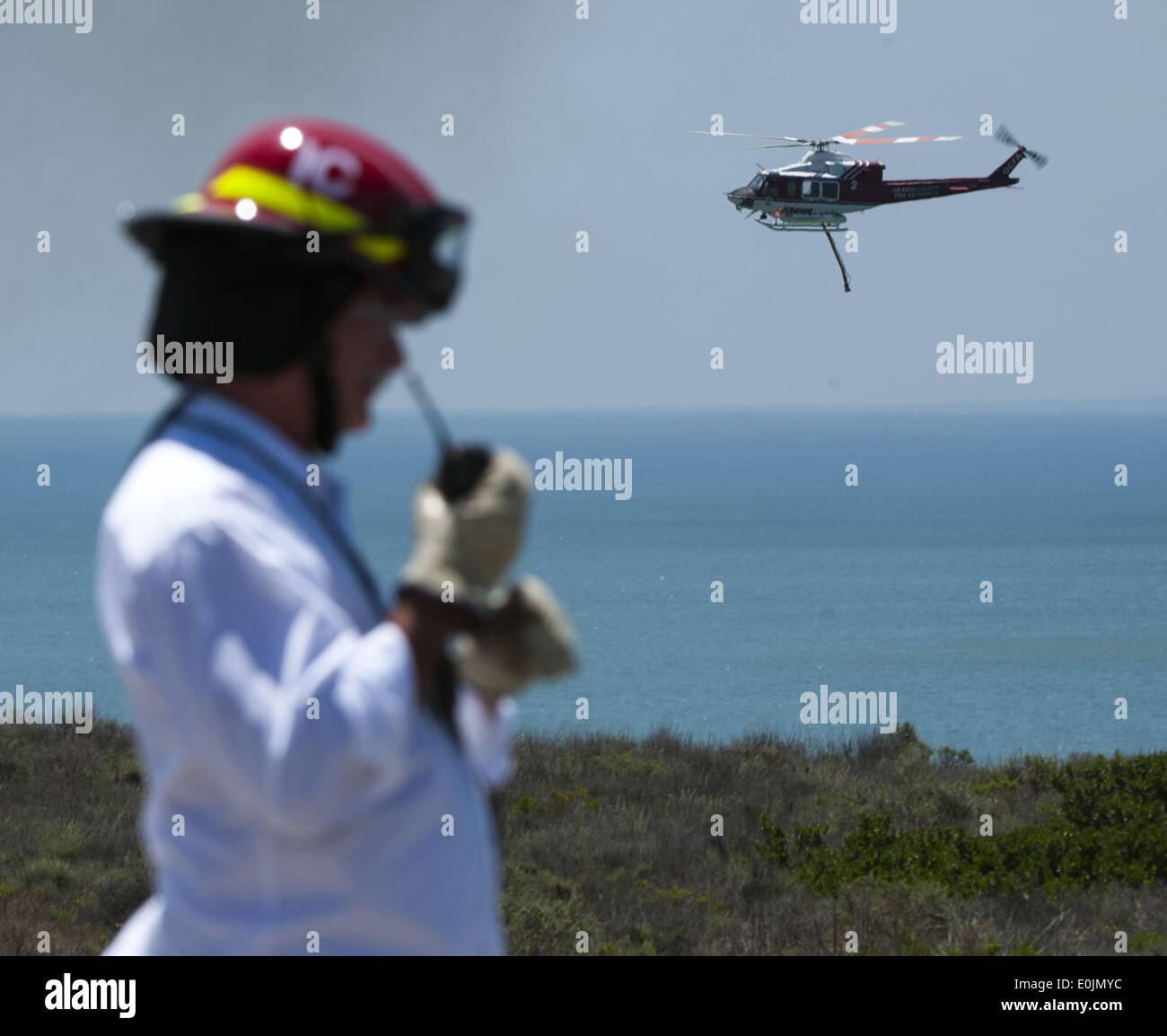 San Onofre, California, USA. 13th May, 2013. A San Onofre Nuclear Generating Station Fire Brigade Captain monitors the radio as an Orange County Fire Authority helicopter passing by on its way to drop fire on Wednesday morning. Multiple Fire agencies, including Federal, State and County, responded to a wildfire on at the San Clemente Check Point that began when a truck on the northbound I-5 Freeway caught fire and passed to nearby vegetation on Wednesday morning. The Pendleton West Fire, had north and south bound trafficstopped, along with Amtrak Passenger Train traffic, as firefighters foug Stock Photo