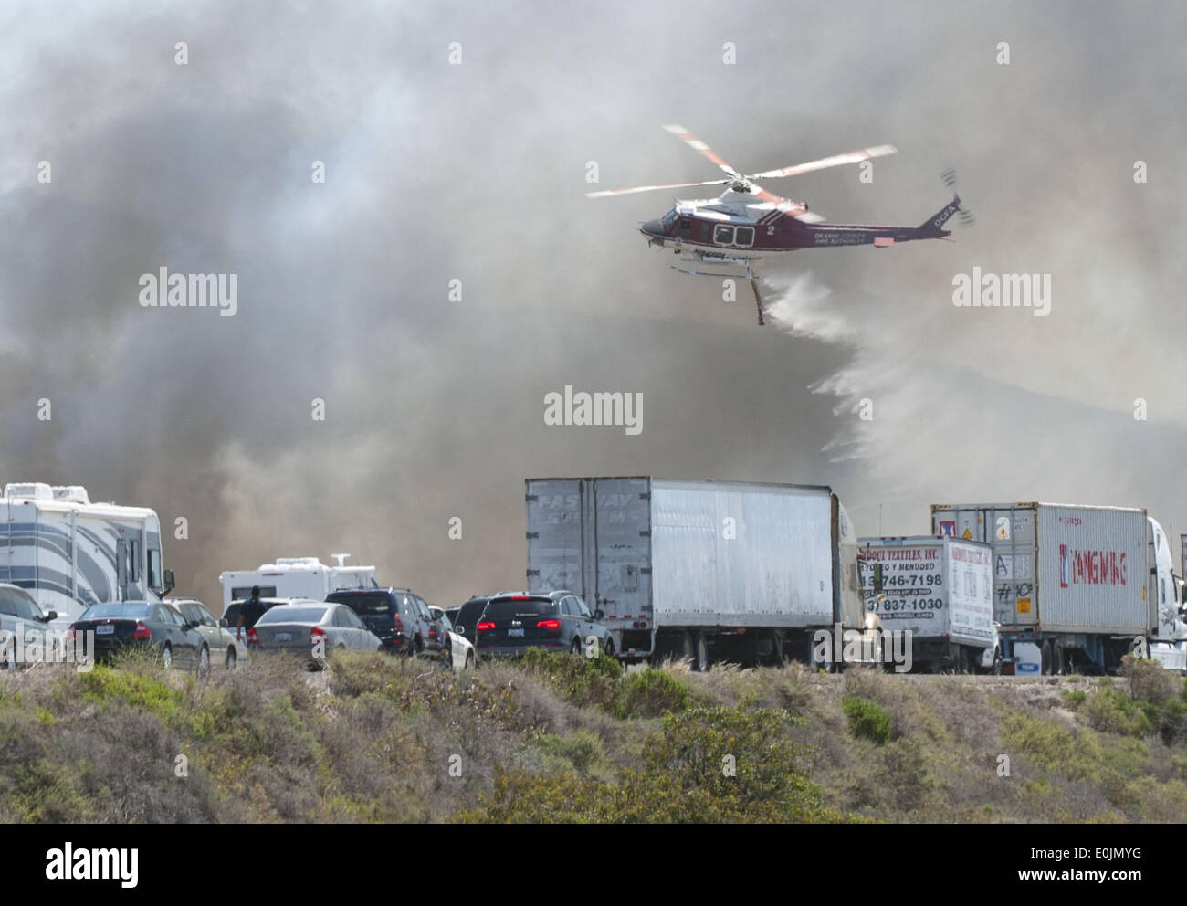 San Onofre, California, USA. 13th May, 2013. A water dropping helicopter comes in low over the I-5 freeway on Wednesday morning dropping sea water on to a fire burning just east along the northbound lanes. Multiple Fire agencies, including Federal, State and County, responded to a wildfire on at the San Clemente Check Point that began when a truck on the northbound I-5 Freeway caught fire and passed to nearby vegetation on Wednesday morning. The Pendleton West Fire, had north and south bound trafficstopped, along with Amtrak Passenger Train traffic, as firefighters fought to contain the 150 p Stock Photo