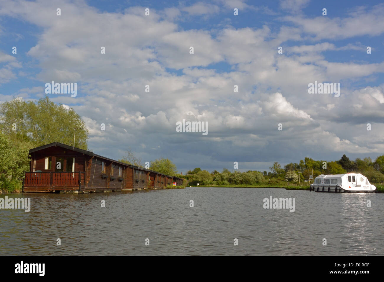 Floating holiday homes and Broads cruiser on the River Ant at Wayford Bridge, Norfolk, Broads National Park Stock Photo