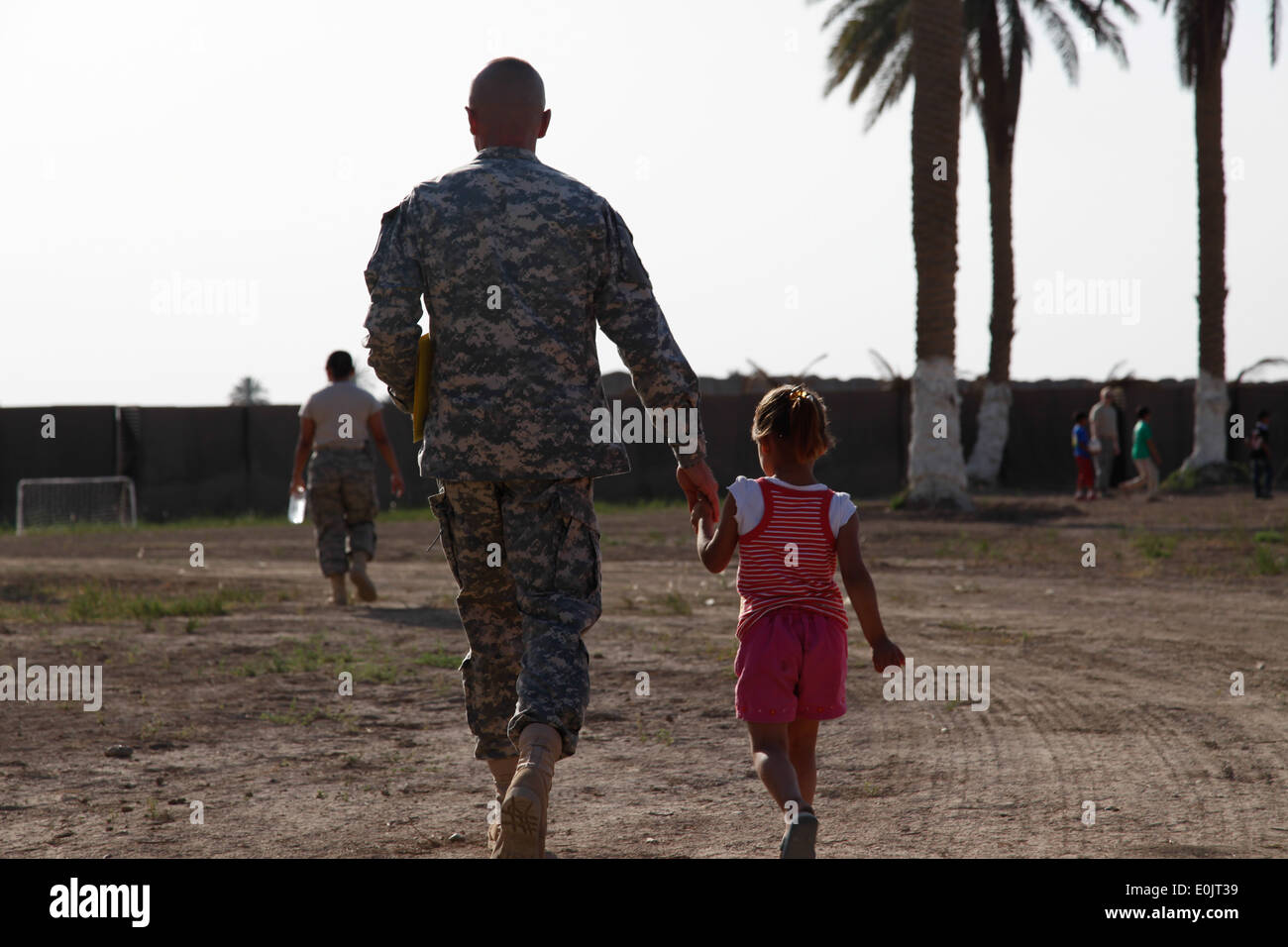 U.S. Army Maj. Gary Farley, chairman of the Iraqi Scouting program in Baghdad walks hand-in-hand with a young girl during the t Stock Photo