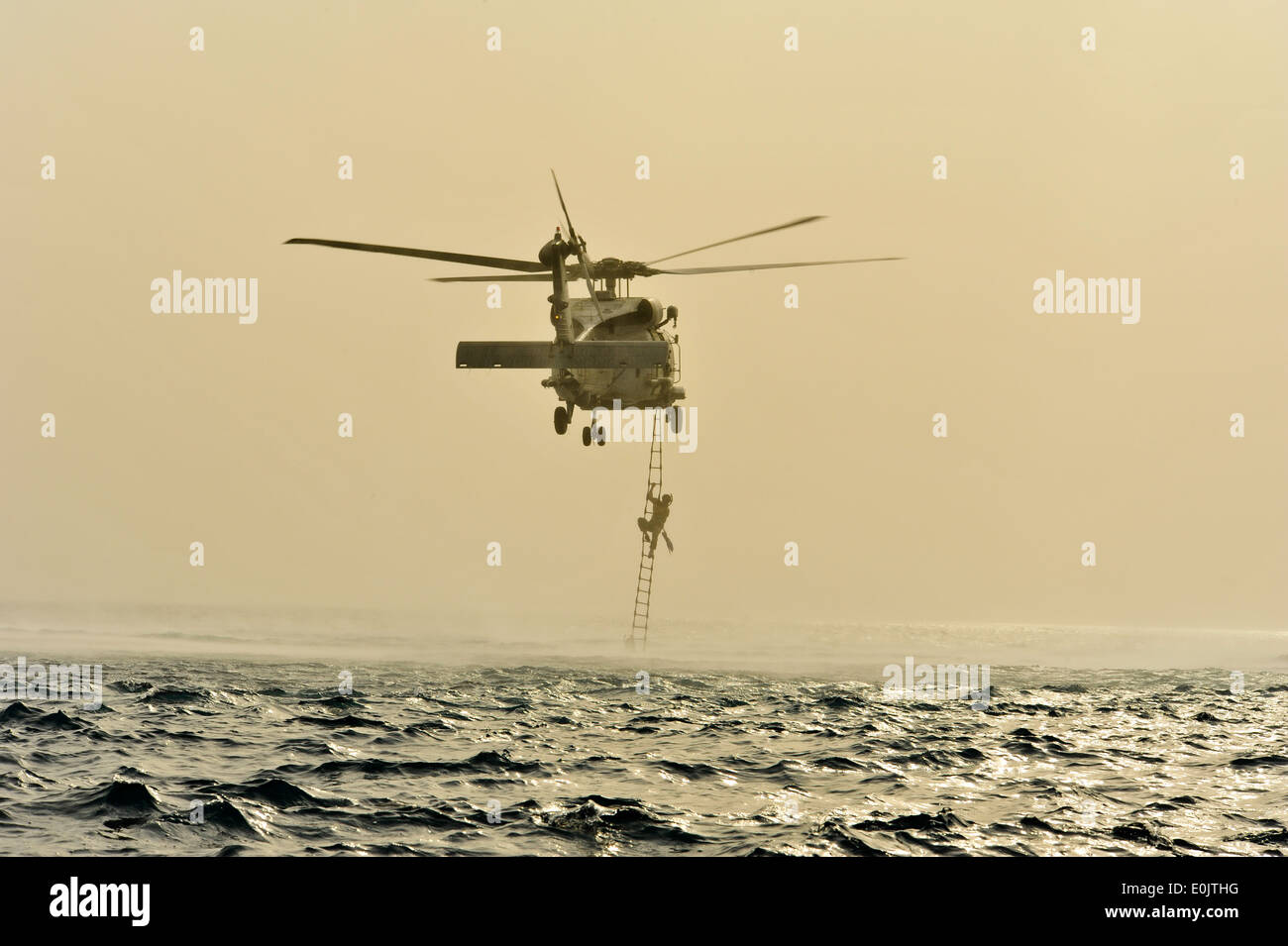 U.S. Air Force pararescue personnel from the 82nd Expeditionary Rescue Squadron, climb a rope ladder to board an SH-60 Sea Hawk Stock Photo