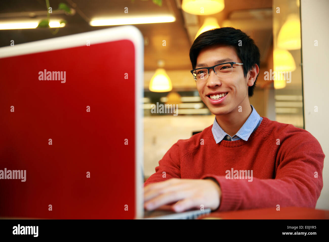 Cheerful young asian man using laptop Stock Photo