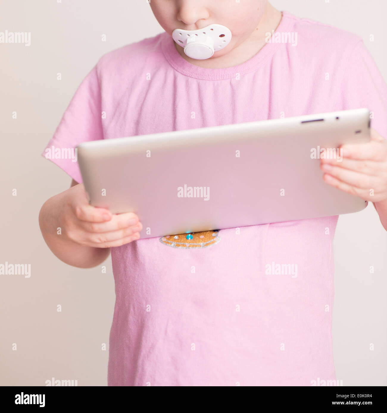 Little girl, 4 years old, holding and using tablet computer in her home. Stock Photo