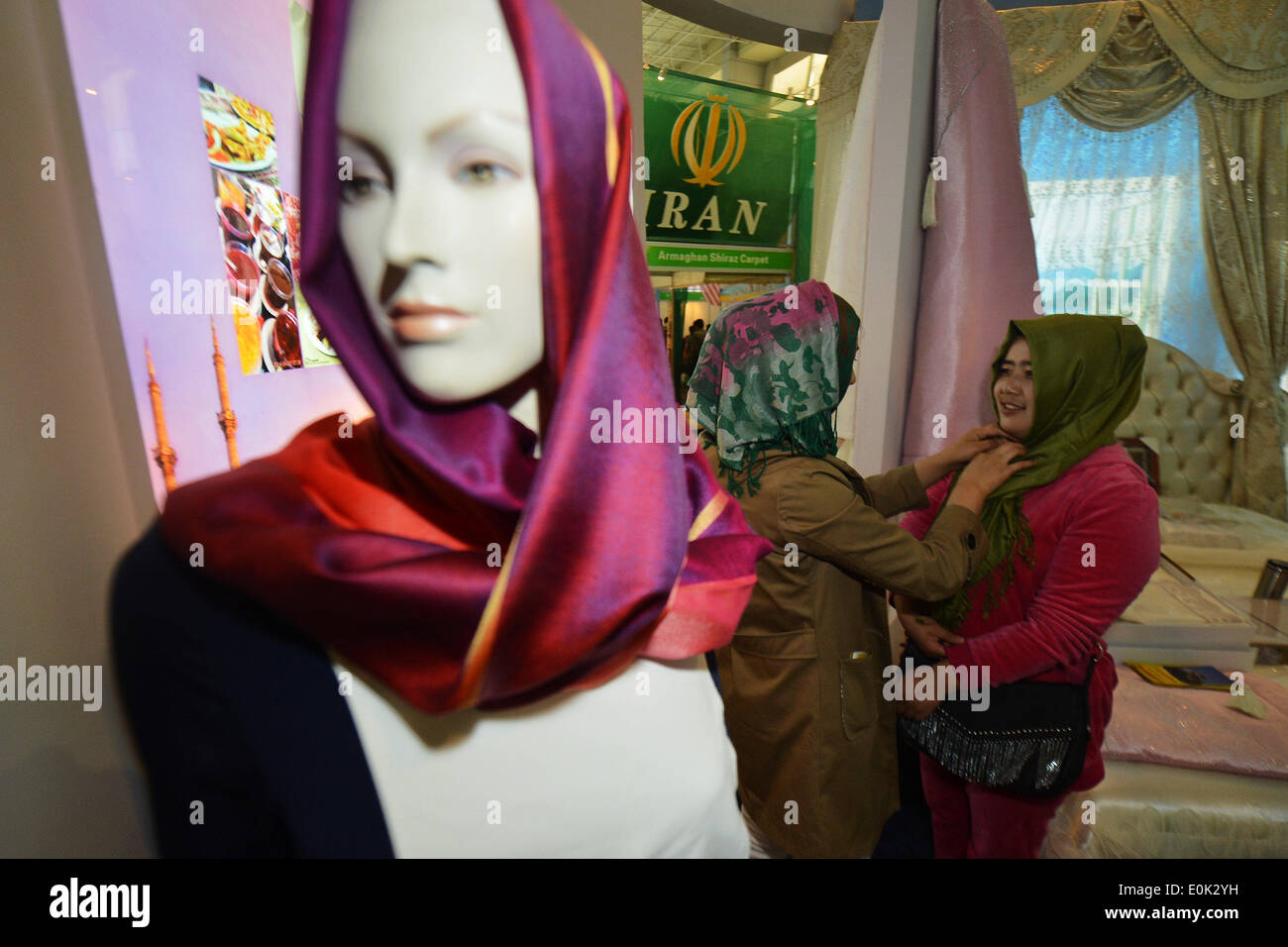 Xining, China's Qinghai Province. 15th May, 2014. Women try on headscarves at an Iranian exhibition stand during the 2014 China International Halal Food and Products Fair in Xining, capital of northwest China's Qinghai Province, May 15, 2014. The three-day fair kicked off Thursday, attracting 960 enterprises from 37 countries and regions. © Wu Gang/Xinhua/Alamy Live News Stock Photo