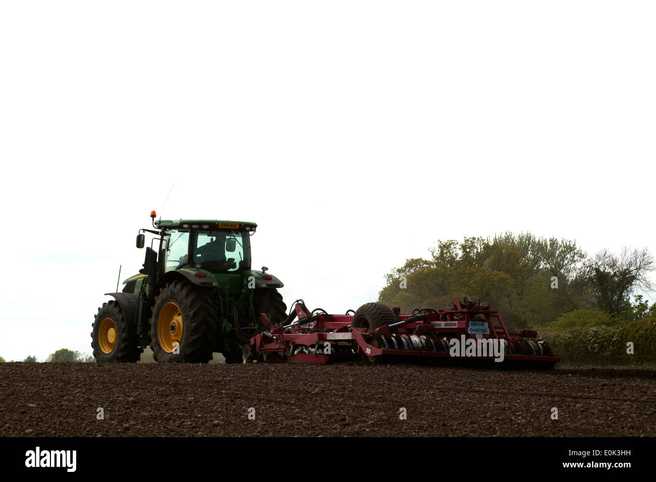 Farmer in tractor harrowing field Stock Photo - Alamy