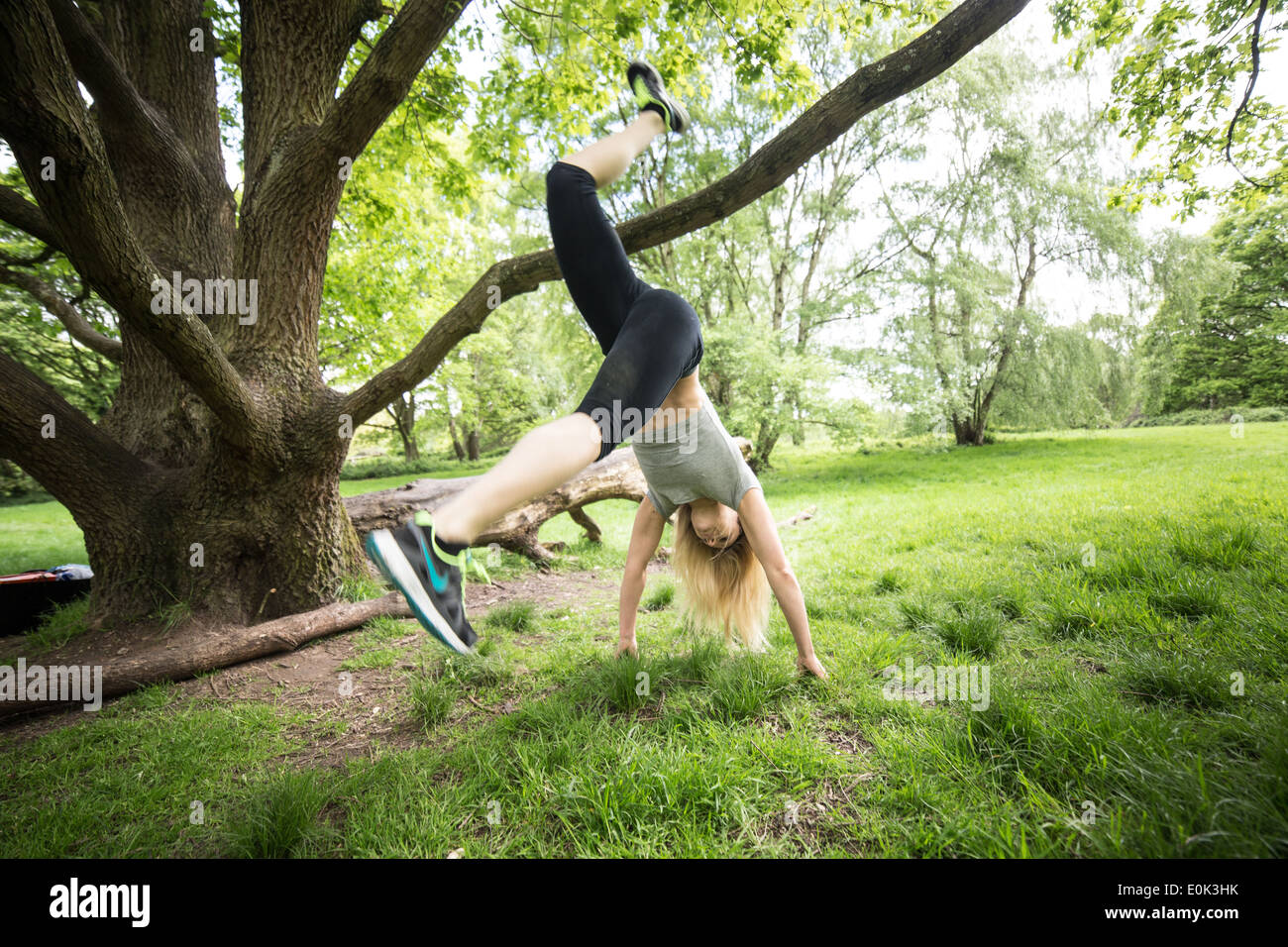 Blonde lady wearing black leggings and a grey crop exercising on hampstead heath. Stock Photo