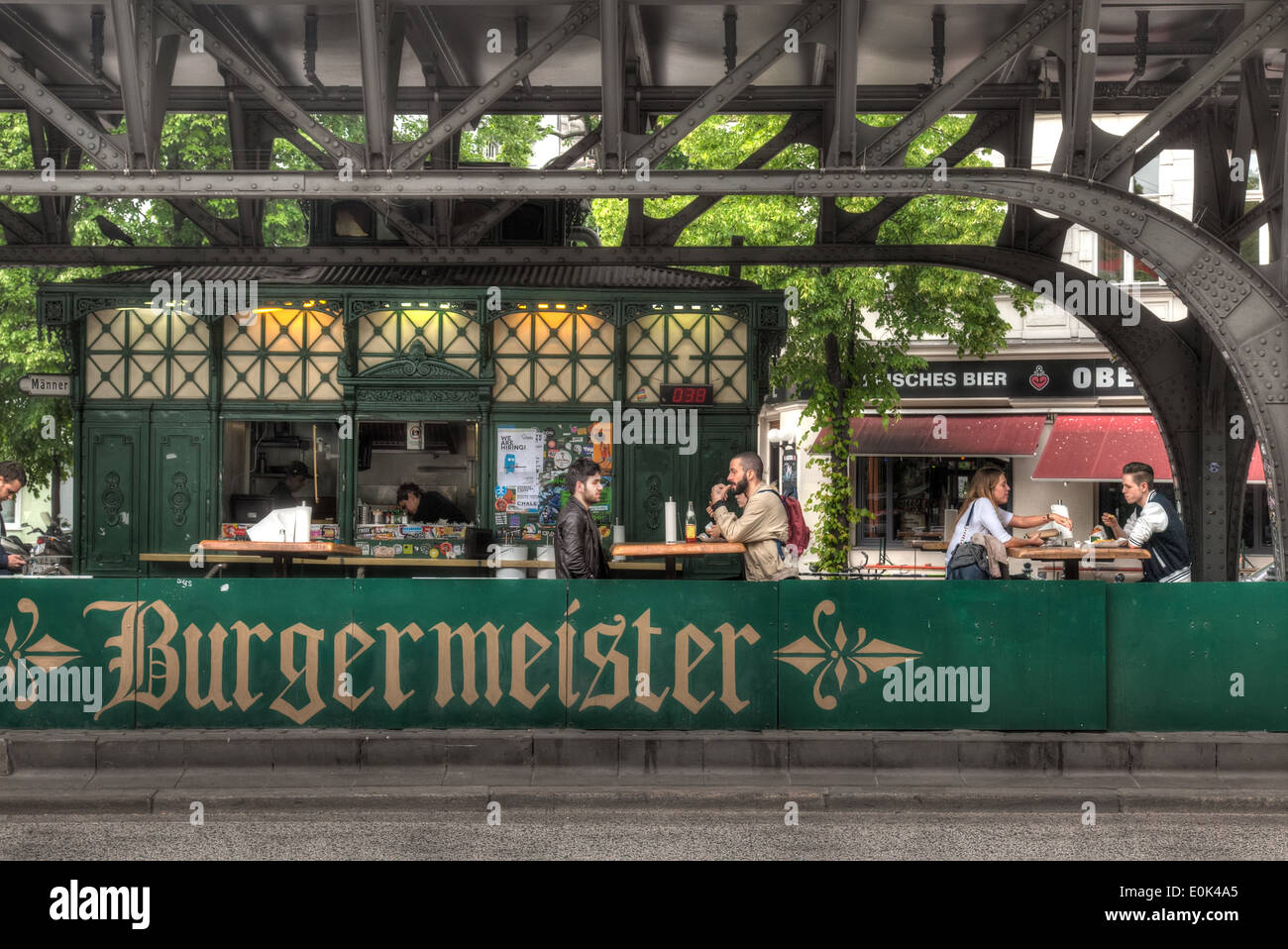 An old toilet block converted into a burger restaurant underneath an elevated railway line (u-bahn) in trendy Kreuzberg Stock Photo