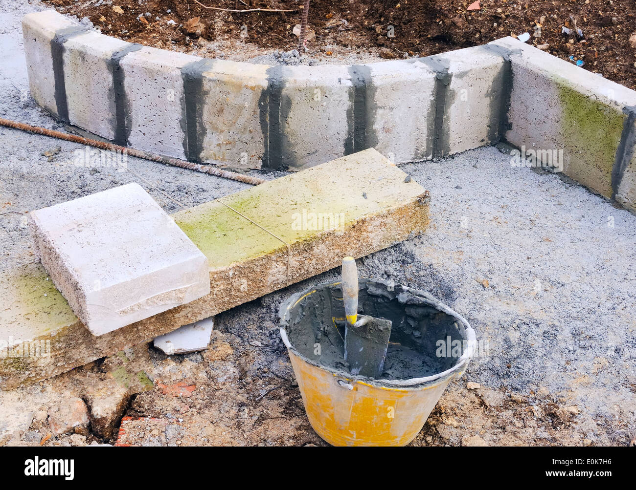 trowel and plastic bucket on newly installed curved sidewalk curb and aligned with direction
