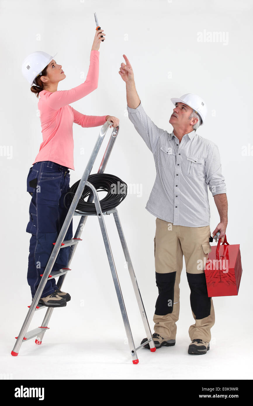 Two electricians working on ceiling lighting Stock Photo