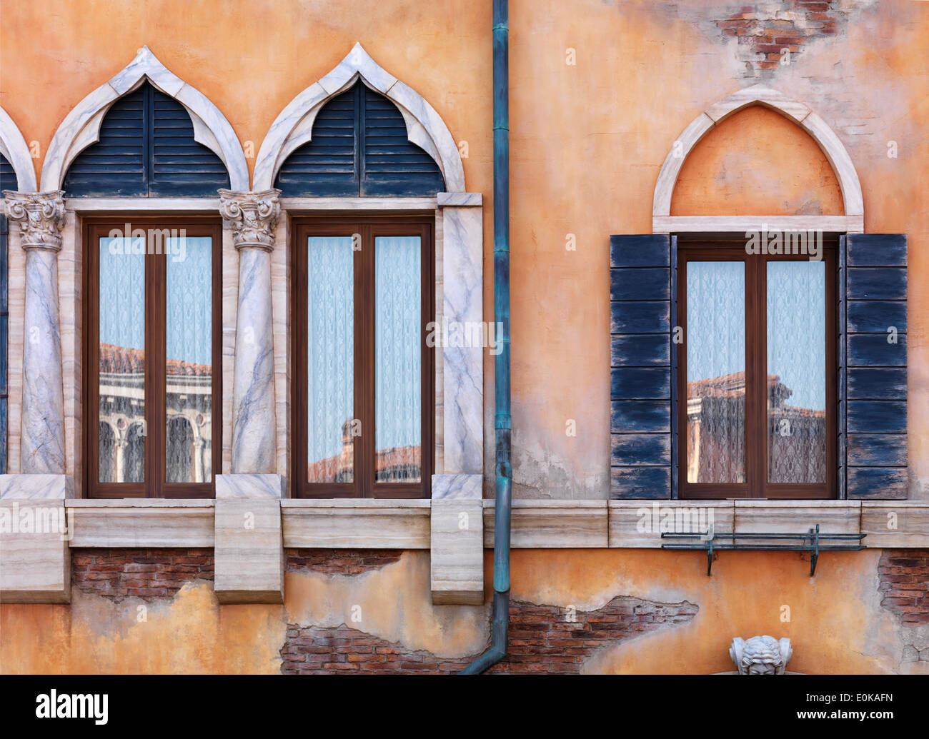 Yellow wall of antique Venetian building with old arched windows, rustic texture Stock Photo