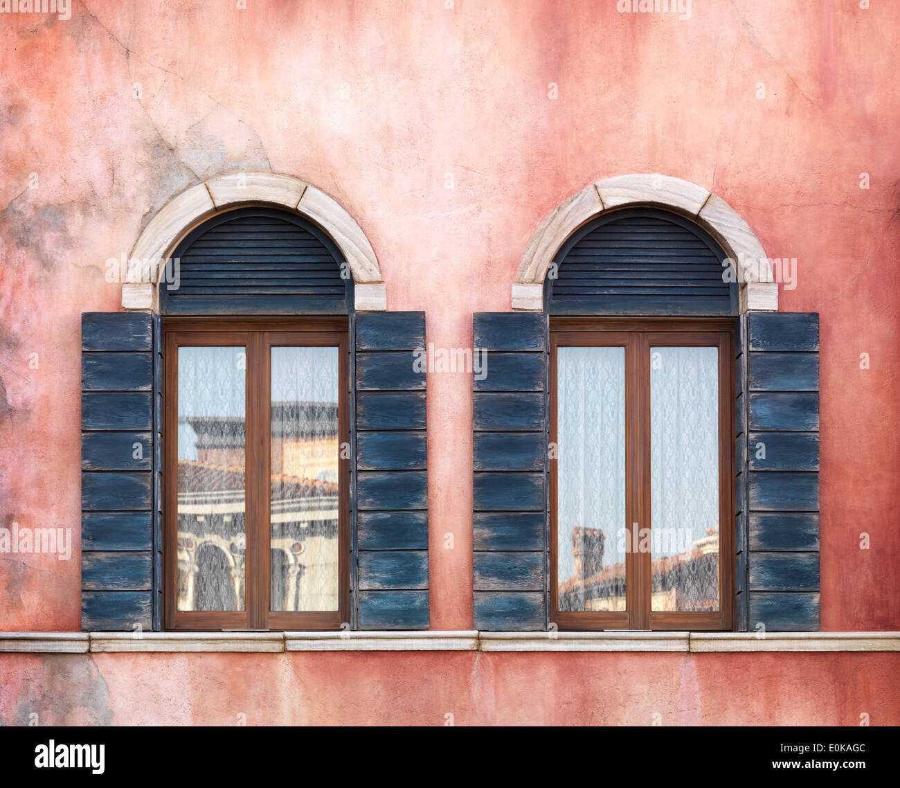 Wall with two old arched windows with shutters, rustic texture Stock Photo