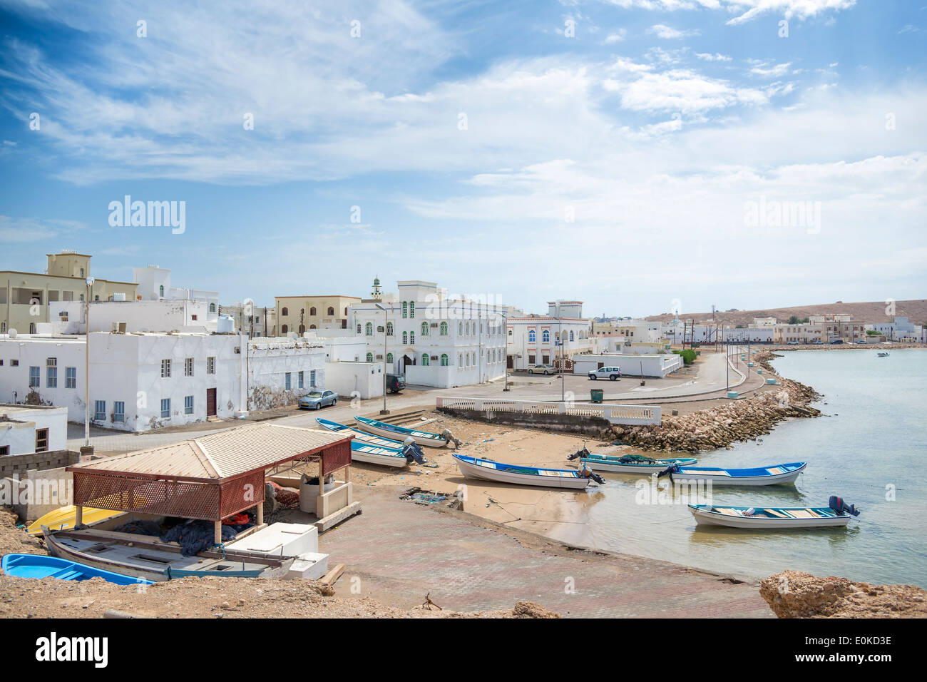 Image of a view to Sur harbor in Oman with sea, mountains, boats, houses and sky Stock Photo