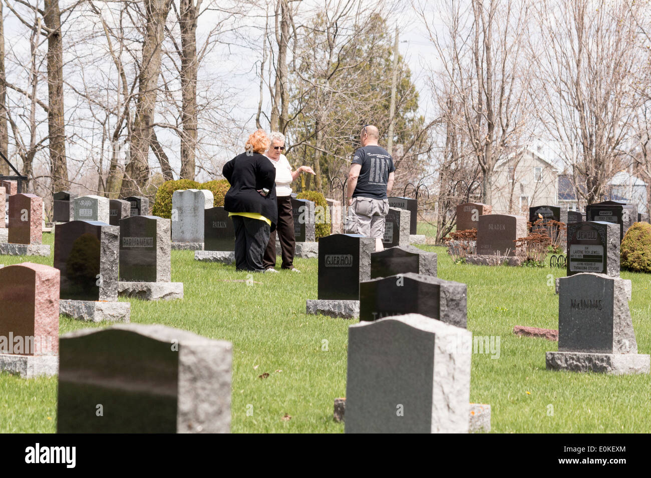 Three people visiting a grave in a cemetary Stock Photo Alamy