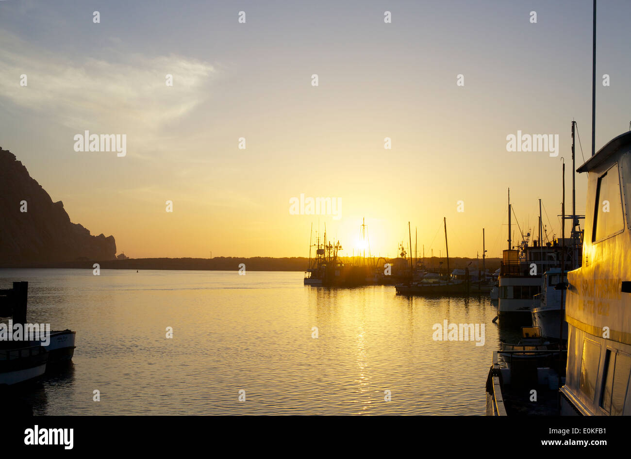 Boats float on the water as the sun sets on the horizon in Morro Bay