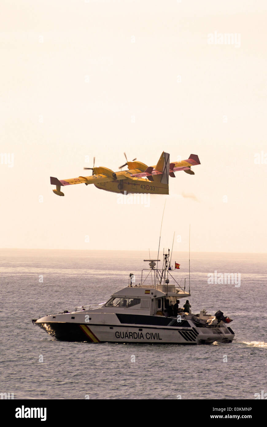 Firebomber flying over Guardia Civil Boat, Andalusia, Spain. Stock Photo