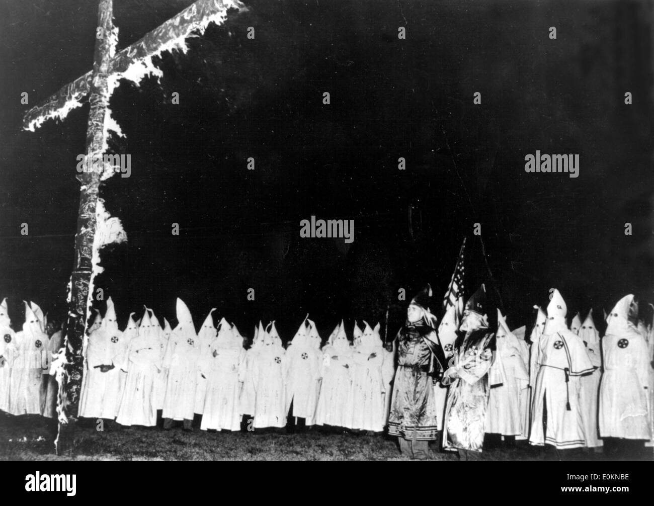 Members of the Ku Klux Klan surrounding burning cross Stock Photo