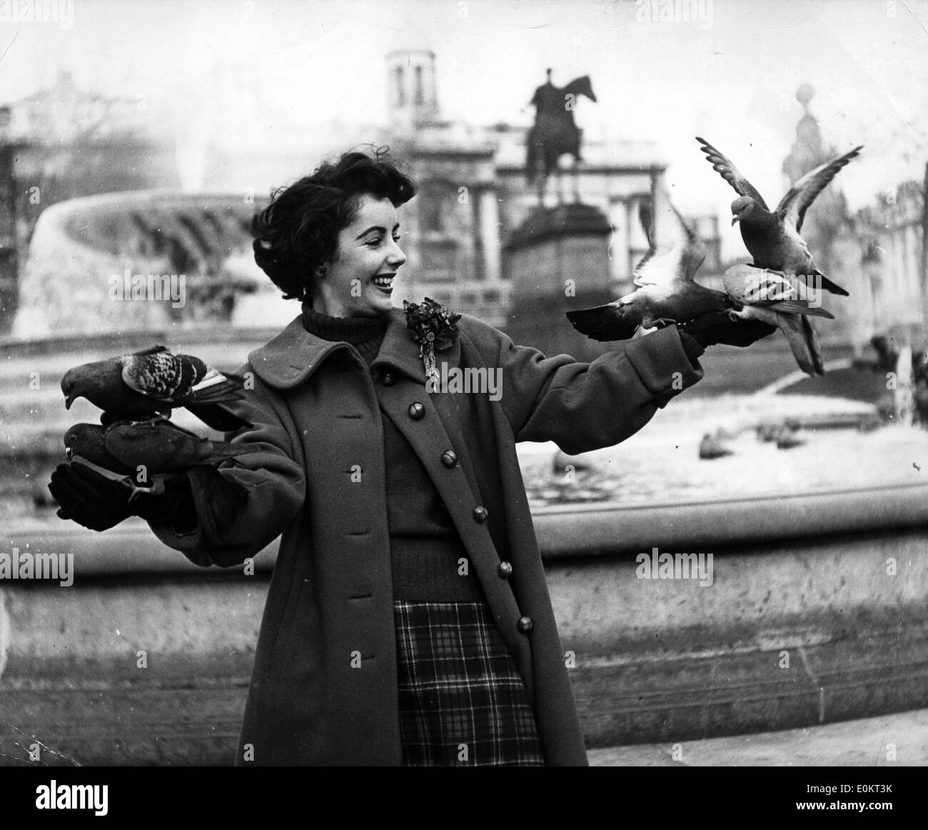 Actress Elizabeth Taylor playing with birds by a fountain Stock Photo