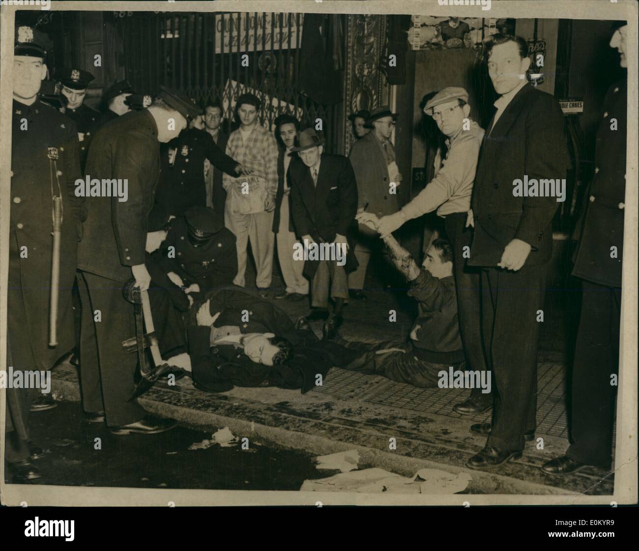 Dec. 12, 1952 - New York cops in gun battle. Seven including by stander injured: Two men, Charles Mason and Richard Linwquist got into a fight outside a bar at 675 Eight Avenue, New York, recently. Two cops arrived to break it up and a moment later Clarence Sims, a Cleveland desperado and Cecil Johnson drove up with the intention of staging a stick up at the bar. Patrolman George Mcauliffe arrived and hearing that Sims was armed backedhim against the well. The arrival of two more patrolman Knox and Conlon, diverted McAuliffe with three slugs, drawing at .45 dropped McAuliffe with three slugs Stock Photo
