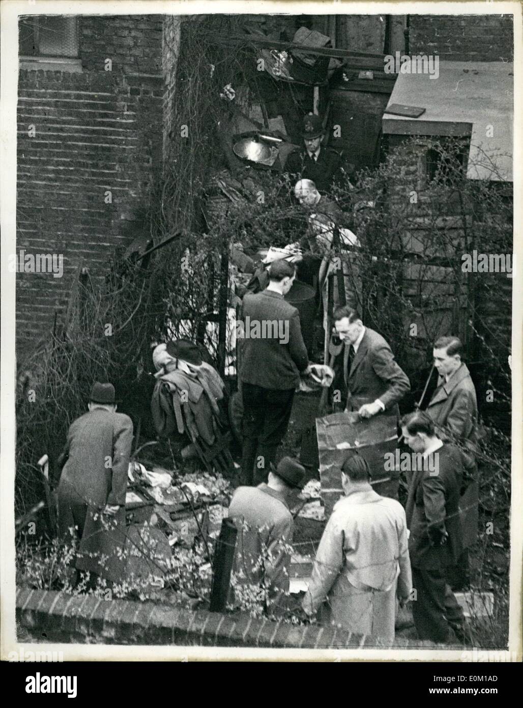 Mar. 03, 1953 - More remains found at house of Death: In a corner of the rubble strewn garden of the Notting Hill murder house today, digging detectives unearthed remains, believed to be human, and possibly those of a fifth victim of the Rillington place strangler. While police in shirt sleeves dug beneath a bush in the brick walled garden they passed bones and pieces of material to Dr. F.E. Camps, the pathologist. Photo shows Police Superintendent Tom Barratt (left) and his men searching the garden today. Holding cardboard is Chief - Inspection P. Law Stock Photo