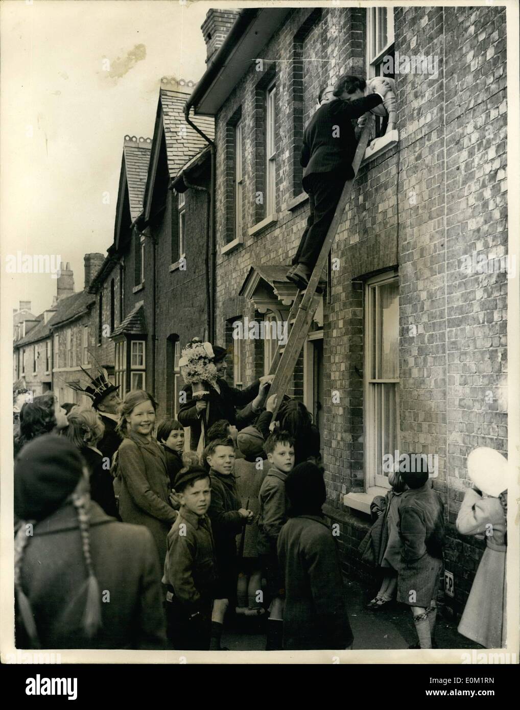 Apr. 04, 1953 - Hocktide ceremony at Hungerford: The ancient traditional festival of Hocktide, was held today at Hungerford, Berks. In accordance with custom, the Tuttimen went through the town with their flower-decorated staves, to collect their ''dues'' a kiss or a penny from the women of the town. Photo shows Tutti-men, Mr. R.A. Bartholomew, receiving a kiss from Mrs. H.J. Sephton during today's ceremony. Stock Photo