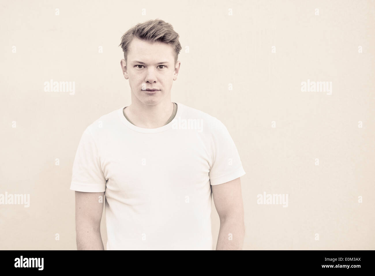 Portrait of young man in front of wall. Pensive expression and looking at camera. Stock Photo