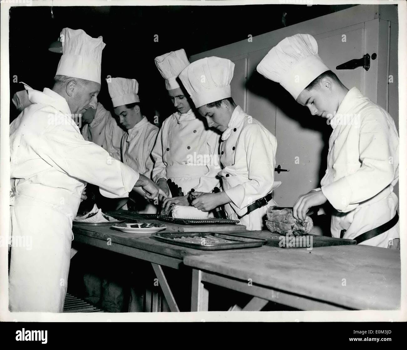 May 05, 1953 - Westminster Technical College Students Prepare to Help in the Queen's Kitchens. : Eleven boys from the Westminster Technical College, Vincent Square, Are to give a hand in the Queen's Kitchens, on Coronation Day. the boys were selected by Mr. J. Vincent head of the College Cookery School - and he decide that it was a job for the boys - as it would probably prove too great a strain for the girl student. Photo shows Chief Lecturer Louis Darsonval who comes from London of French Parents gives  of instructions to some of the boys at the College today. they are right to Left Stock Photo