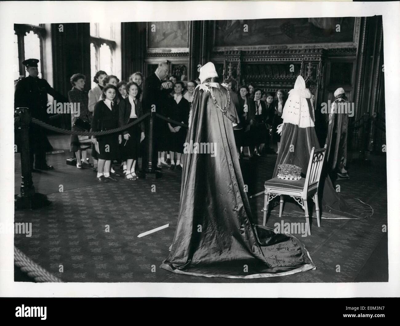 May 05, 1953 - Children at Robes and Insignia exhibition: Schoolchildren from the Hyde Park Girls' school at Doncaster, Yorkshire, who are in London on a week's holiday, are shown over the Exhibition of robes and Insignia in the Royal Robing Room, House of Lords, by Mr. Joseph Mayes, a member of the staff of the Palace of Westminster. The robes, from left to right are: The Royal Victorian Order (blue with red edgings and gold tassels), which Goronet; and the order of St. Michael and St. George (Royal blue). The exhibition is open to the public. Stock Photo