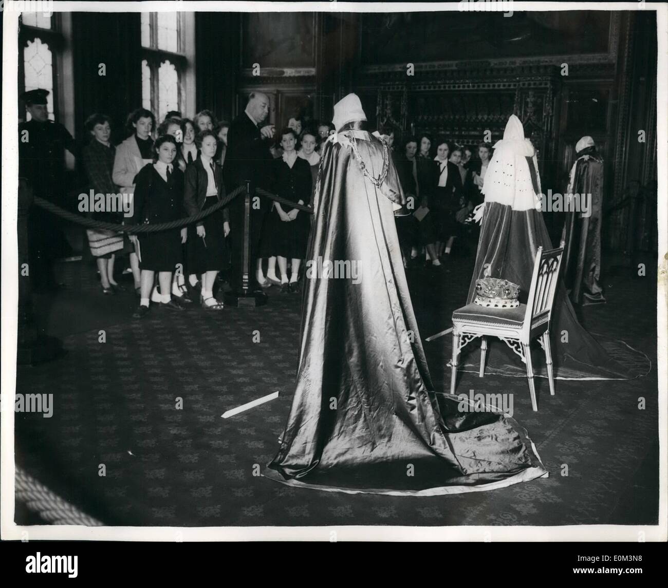 May 05, 1953 - Children at Robes and Insignia exhibition: Schoolchildren from the Hyde Park Girls' school at Doncaster, Yorkshire, who are in London on a week's holiday, are shown over the Exhibition of robes and Insignia in the Royal Robing Room, House of Lords, by Mr. Joseph Mayes, a member of the staff of the Palace of Westminster. The robes, from left to right are: The Royal Victorian Order (blue with red edgings and gold tassels), which Goronet; and the order of St. Michael and St. George (Royal blue). The exhibition is open to the public. Stock Photo