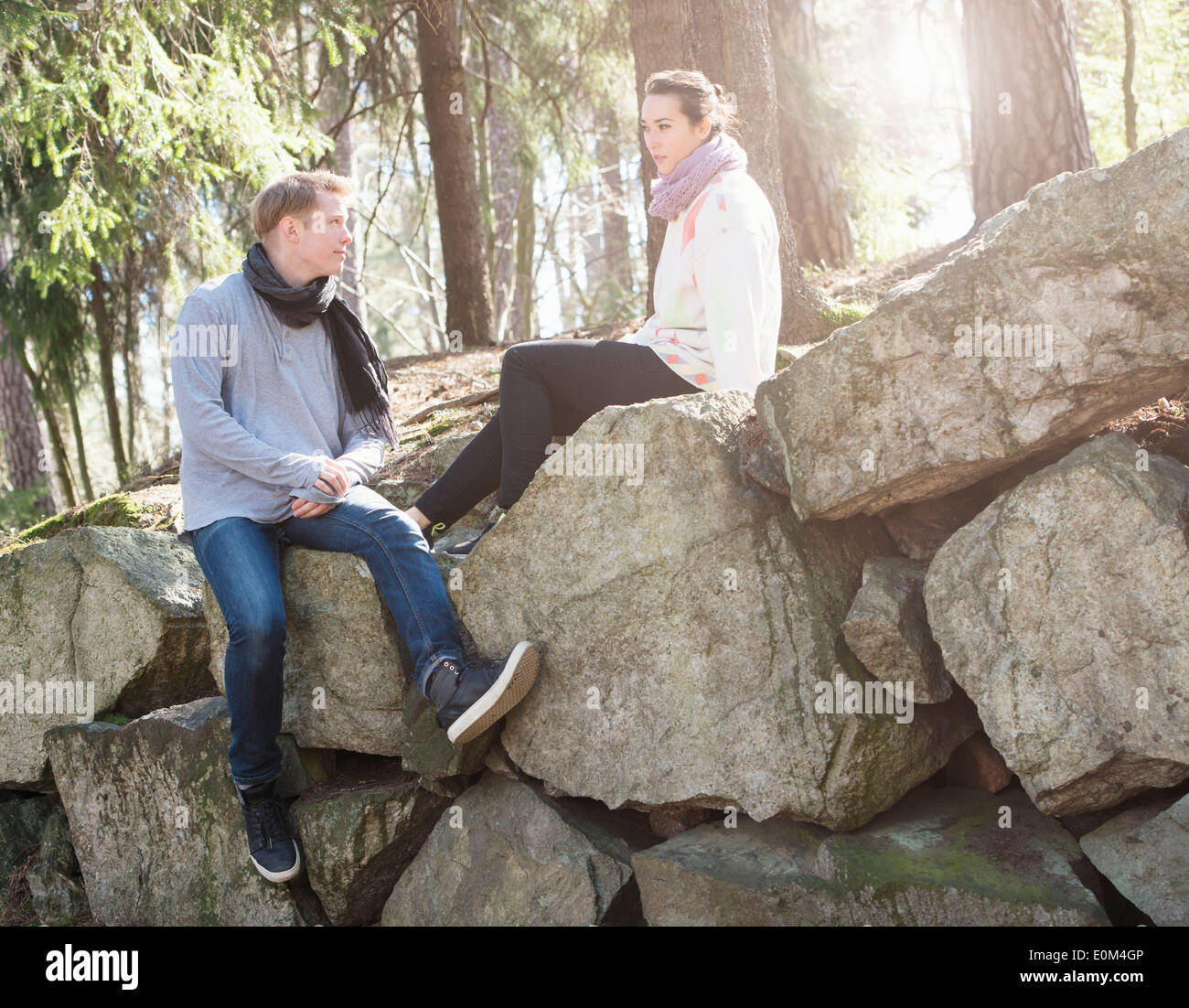 Young couple in nature resting on big rocks in woods during a trek. Stock Photo