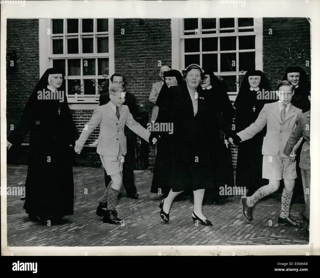 Sep. 09, 1953 - Queen Juliana Goes Dancing - with the Orphans. Democratic Royalty.: Queen Juliana of the Netherlands is seen here in a very democratic attitude - as she joins in a dance with boys and girls - and Catholic Sisters - when she paid a visit to an Orphanage in Amsterdam recently. Stock Photo