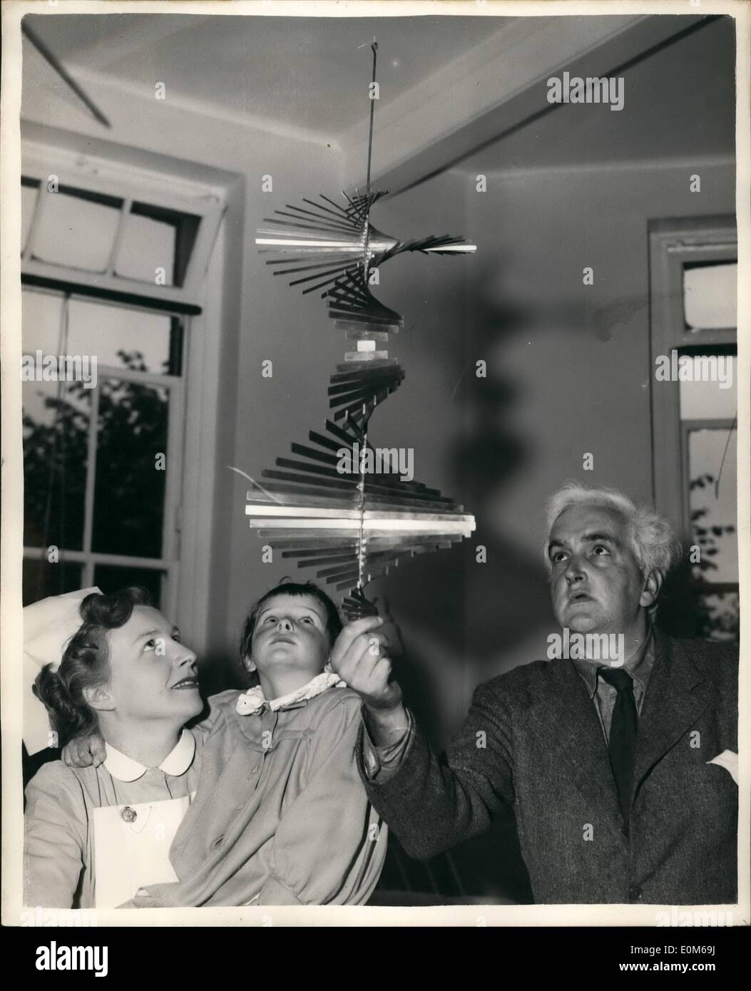 Sep. 09, 1953 - ''Mobiles'' at London Hospital. ''Art'' for the patients: Dr. Simon Yudkin children's specialist has installed a number of ''Mobiles'' - ( shapes constructed from twisted metal and wire ) in the Whittington Hospital, Highgate. The idea is that they could help the children create an interest in their surroundings, Scultor Kenneth Martin a Hampstead Artist arranged the exhibition. Photo shows Kenneth Martin the designer of the ''Mobiles'' - shows one of his pieces to Staff Nurse Brenda Hanley and patient Patricia Norris ( 6 1/2 ) at the hospital today. Stock Photo