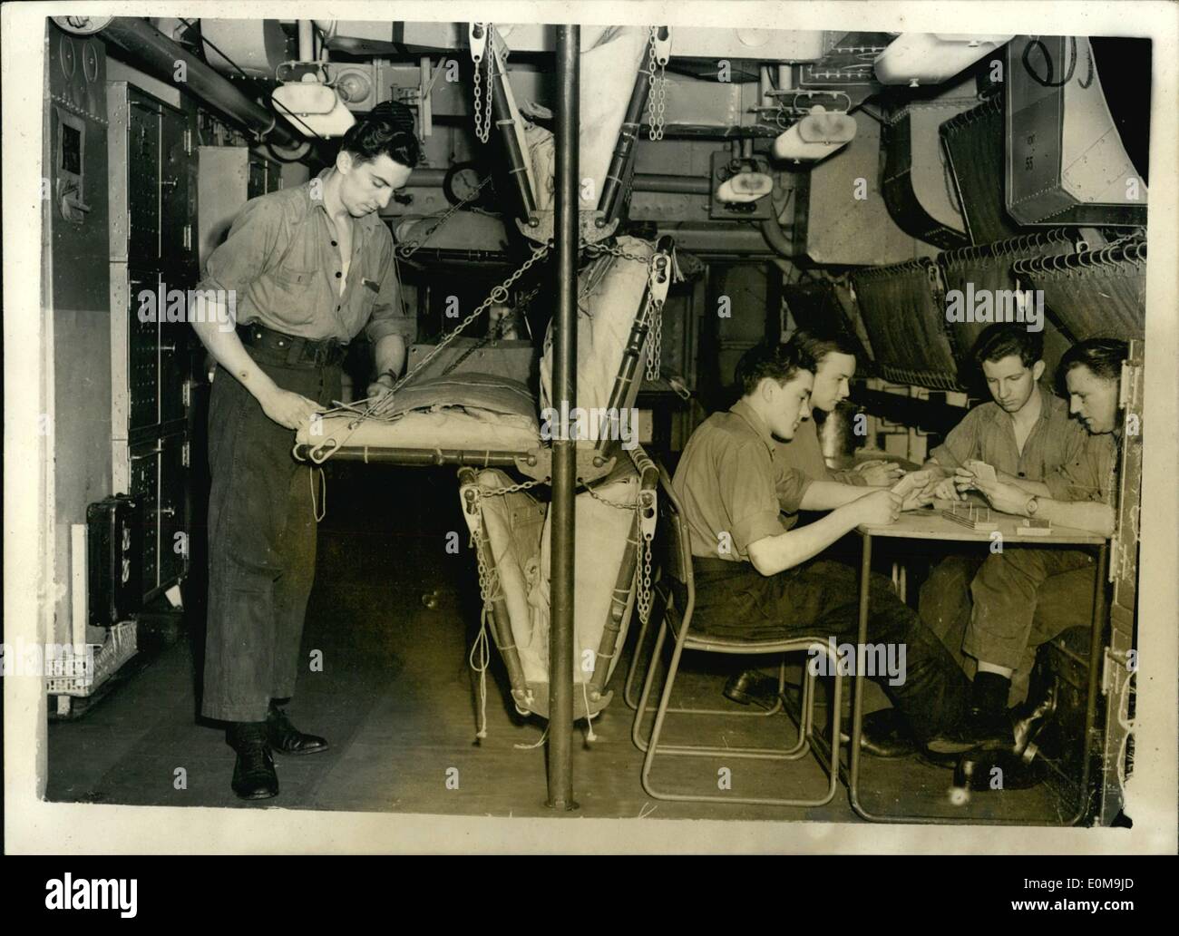 Apr. 04, 1954 - Canvas Bunks Take Place of Hammocks in New British Aircraft Carriers... To improve living conditions of ships' companies - canvas bunks are to replace the traditional hammocks in the new aircraft carriers the Centaur and Albion... The bunks are so designed that they can be stowed when not in use and the extra space for which 'nests' of tables are provided - can be use for recreational purposes... Keystone Photo Shows: Scene in the Communication Mess Deck at Telegraphists play cards - using one of the portable tables - while on left a colleague lowers his canvas bed.. Stock Photo