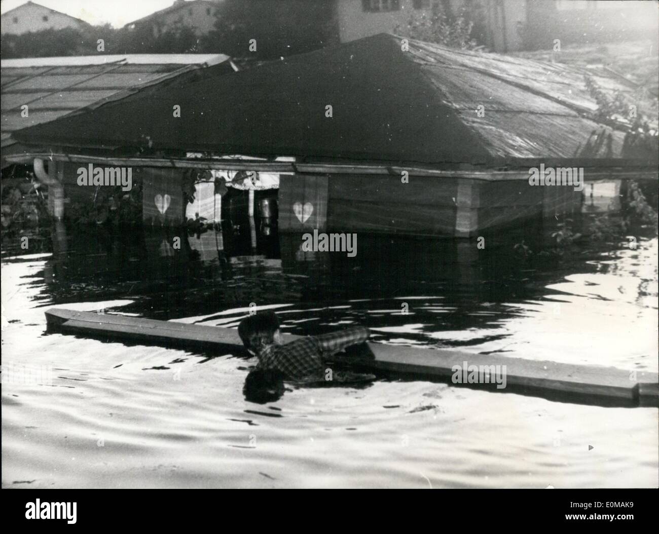 Jul. 07, 1954 - Deggendorf new in the centre of the flood catastrophe: When the right side of the ''Begenbach-dam'' in Deggendorf broke the Northern part of the town Schachingen was flooded. Beats are rare. A man train in the morning clang up to a beam to get to his flooded house ti save what he still could save. Stock Photo