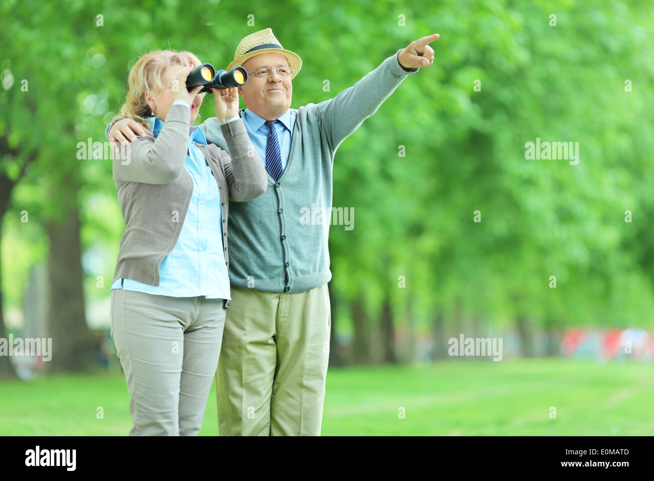 Woman looking through binoculars with her husband in park Stock Photo