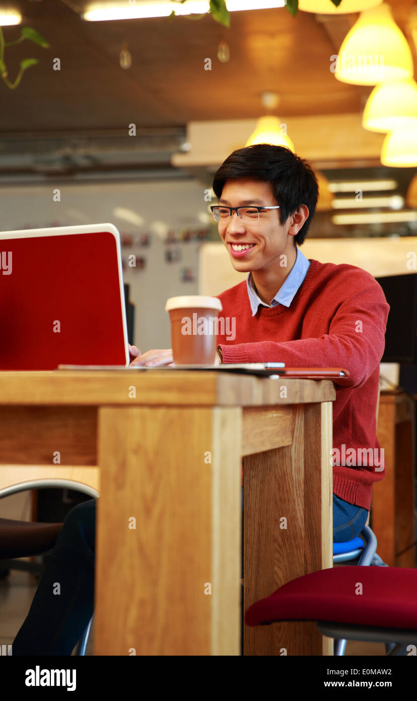 Smiling asian man in glasses working on laptop Stock Photo