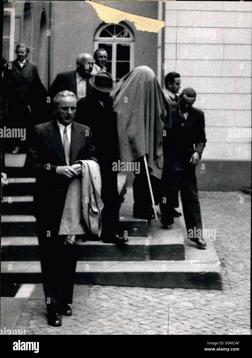 Jun. 19, 1954 - Pictured here, hiding his face, is Gustav Scholling, a blind 60 year old who is in court for ''killing'' his life companion 69 year old Magdalena Jonissek, who was suffering from severe meningitis. Magdalena wished to be killed to escape the pain. The court imposed the lightest sentence of two months in jail for him. He wrapped a noose around her neck and performed the act. Scholling is shown here with a coat over his head as he left the court building. Stock Photo