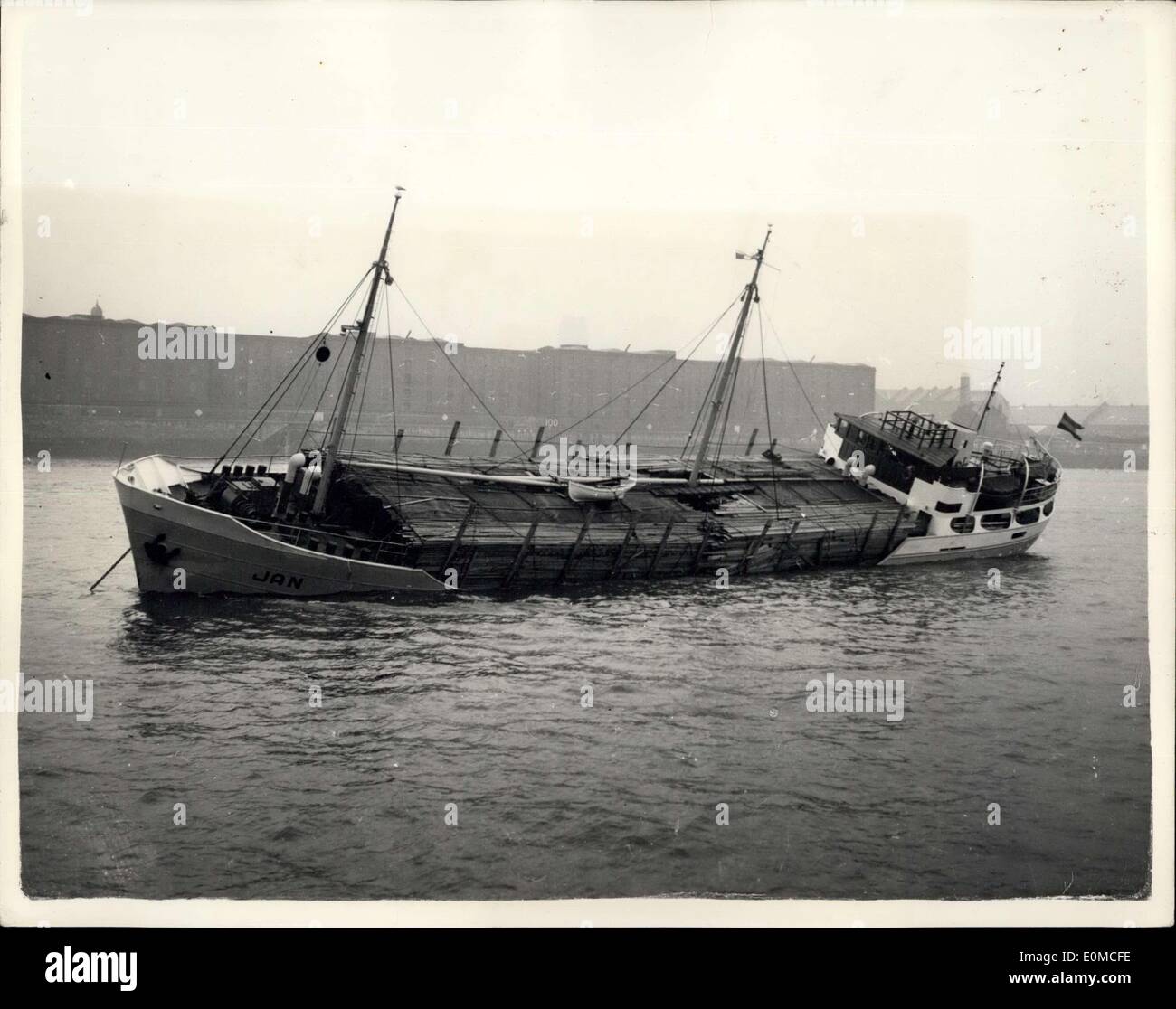 Aug. 21, 1954 - Dutch Ship Arrives in the Mersey with a List of 30 Degrees: Battered by gales in a ten-day trip from Sweden, the Dutch motor vessel Jan arrived in the Mersey, Liverpool, yesterday, with a list of more than 30 degrees.The list was caused by her deck cargo of timber being swollen by the heavy rain which came with the gale.This ship carries a crew of 11 - including the young wife of the Captain L.Bergsma, who has travelled thousands of miles with him on his voyages. Photo Shows Photographed from the river, the Jan lists to port with part of her cargo of timber awash. Stock Photo