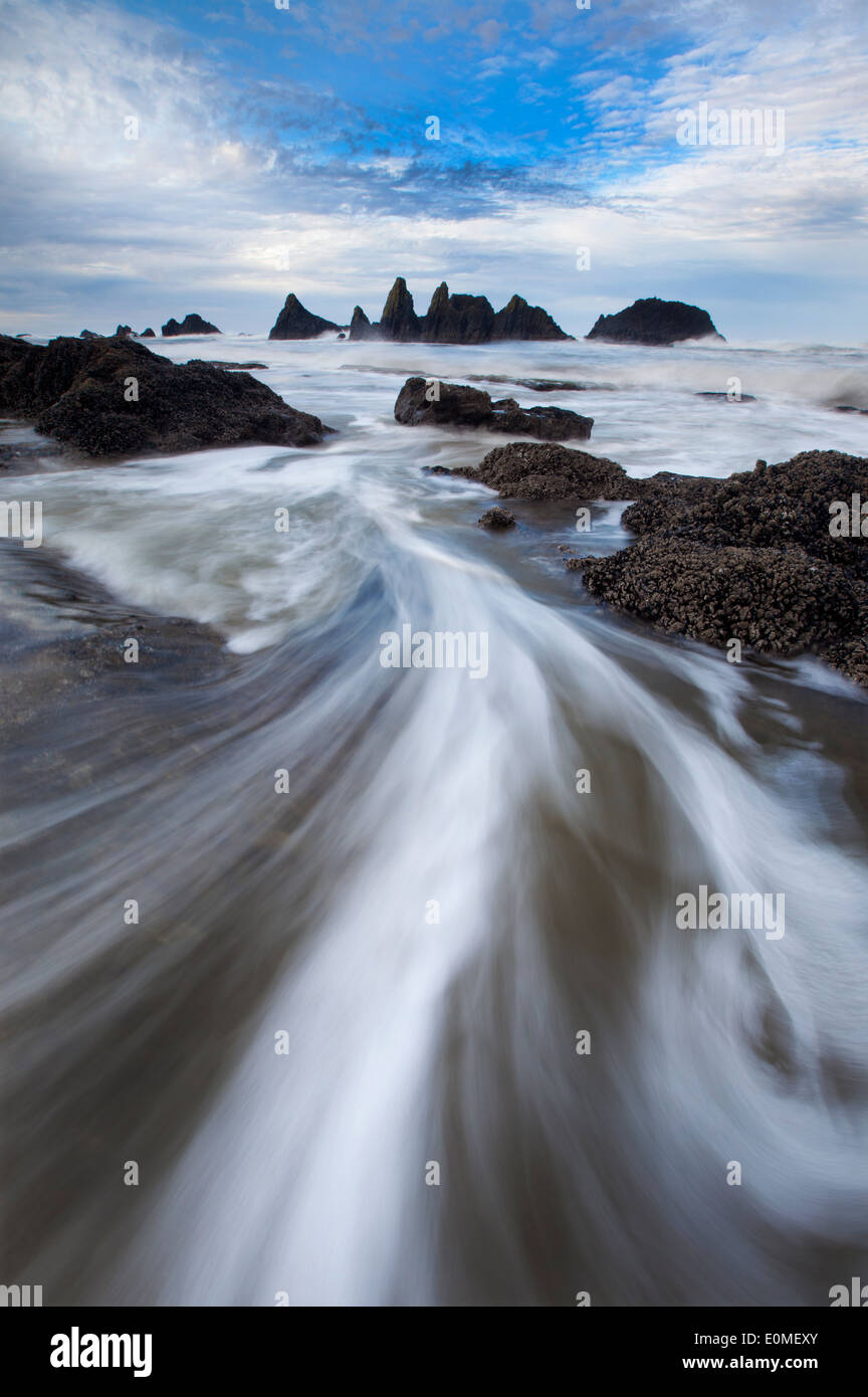 Water rushes through the legs of the photographer and back to sea, Seal Rocks State Park, Oregon, USA Stock Photo