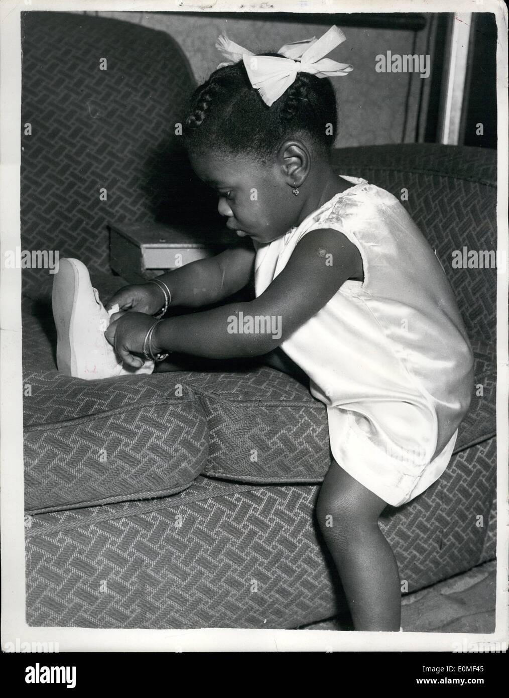 Dec. 12, 1954 - 10-12-54 Coloured youngster prepare for Charity debut. Candy ties her shoe lace. A trio of coloured youngsters were to be seen at their London house this morning preparing to make their debut on the stage of the Metropolitan Theatre, Edgeware, on Saturday. They are Binkie (6); Bonny (3) and Candy (22 months). They are to take party in a Charity matinee in aid of St. Dunstan's. Their father is bass player and singer Sonny McKenzie and their uncle is variety artist Mike McKenzie Stock Photo