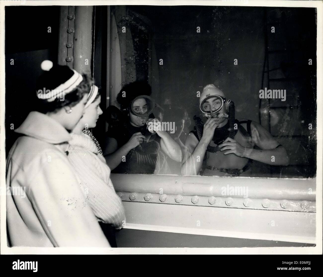 Dec. 30, 1954 - Opening of the National Boat Show at Olympia. Eating Bananas under water: Photo Shows Pauline Ady of Twickenham, who is a Radio-therapist and Barry Blair an aeronautical engineer from Hatfield - take it easy and eat bananas in the huge water tank - at the opening of the National Boat Show at Olympia this morning. They are both members of the Sub-Aqua Club. They are demonstrating the latest sport - 'Skin-Diving' an aqua-lung which enables divers to stay under the surface for hours. Watching L-R: Roberta Basford and Carol Park. Stock Photo